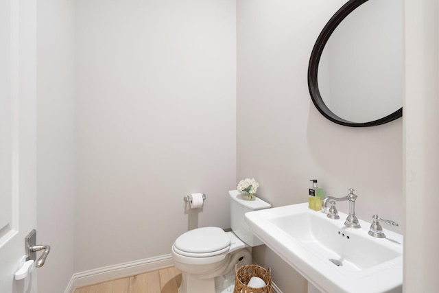 bathroom featuring wood-type flooring, toilet, and sink