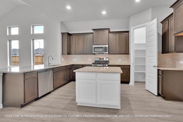 kitchen featuring stainless steel appliances, sink, light wood-type flooring, and kitchen peninsula