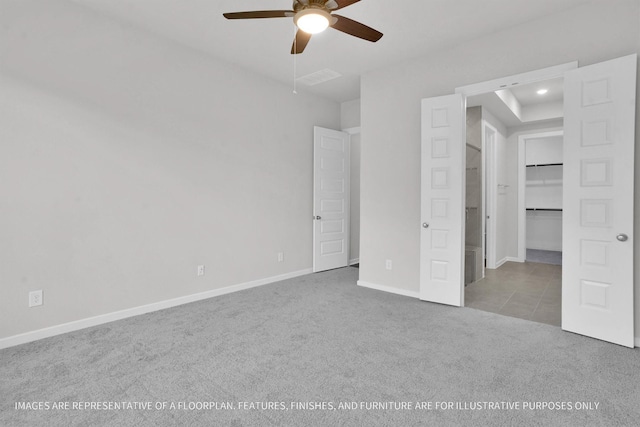 unfurnished bedroom with light carpet, a walk in closet, and ceiling fan