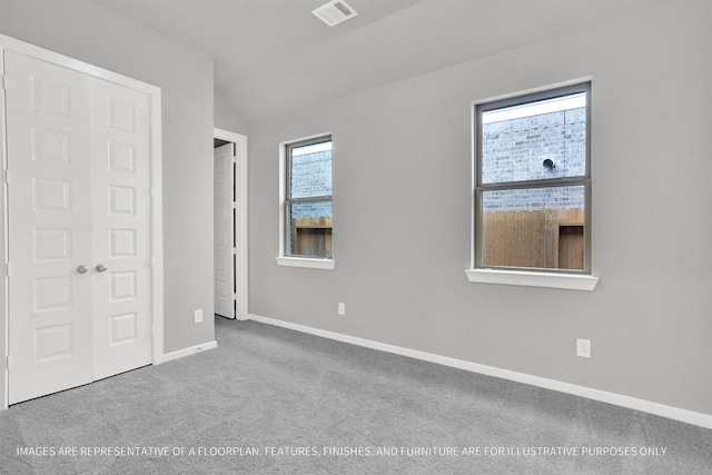 unfurnished bedroom with vaulted ceiling, carpet, visible vents, and baseboards