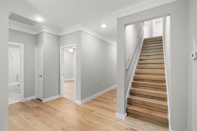 staircase featuring ornamental molding and hardwood / wood-style floors