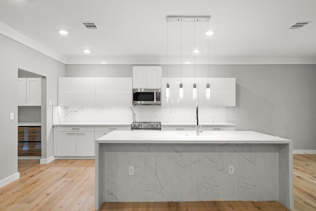 kitchen with range, decorative light fixtures, a center island with sink, and white cabinets