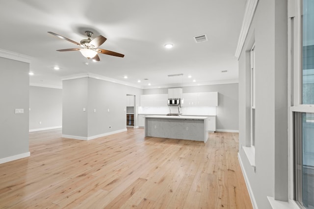 unfurnished living room featuring ornamental molding, ceiling fan, and light wood-type flooring