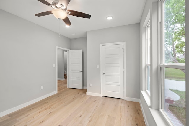 unfurnished bedroom featuring multiple windows, a closet, ceiling fan, and light hardwood / wood-style floors