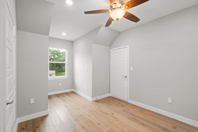 empty room with ceiling fan, lofted ceiling, and light hardwood / wood-style floors