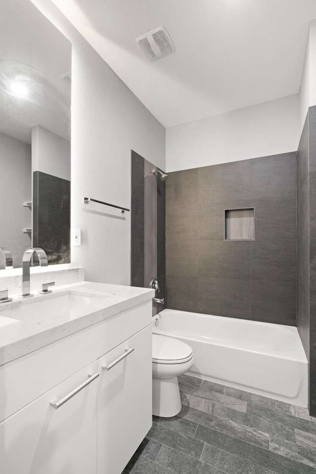 full bathroom with vanity, tiled shower / bath combo, and toilet