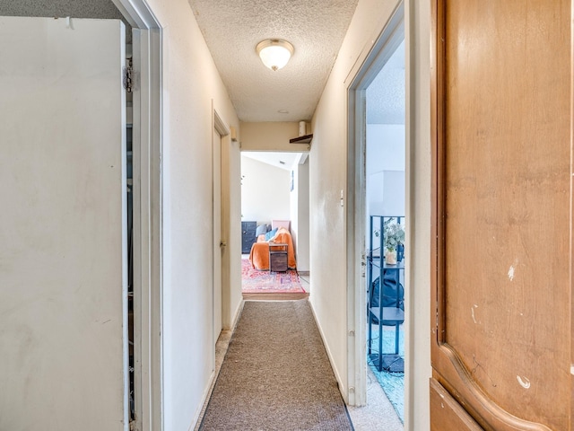 corridor with carpet floors and a textured ceiling