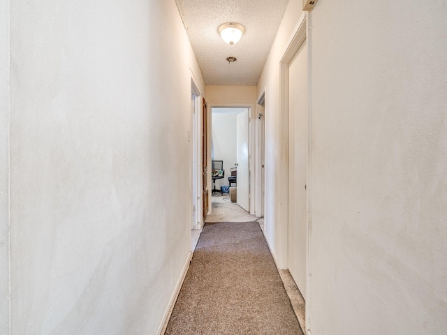 hall with light colored carpet and a textured ceiling