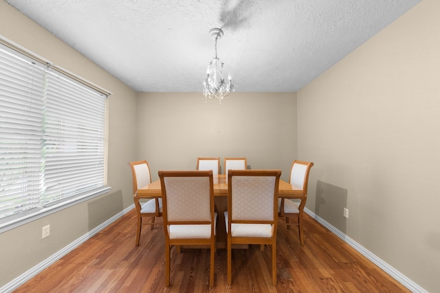 dining space featuring a textured ceiling, wood-type flooring, a chandelier, and plenty of natural light