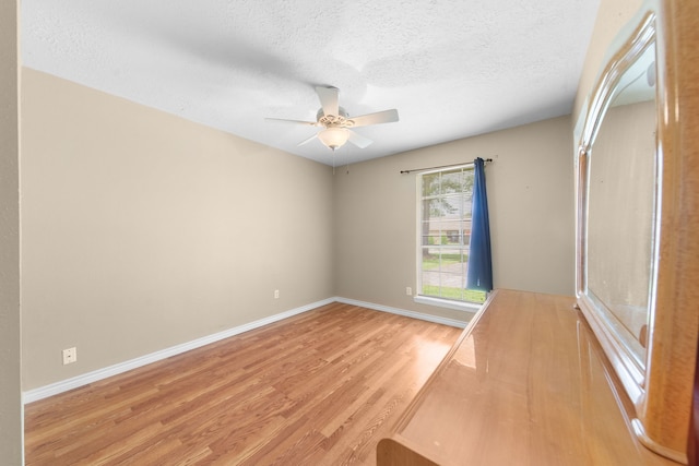 spare room with ceiling fan, a textured ceiling, and light wood-type flooring