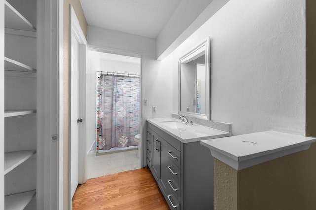 bathroom featuring walk in shower, vanity, toilet, and hardwood / wood-style floors