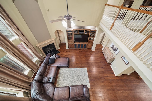 living room with dark wood-type flooring, ceiling fan, and a high ceiling