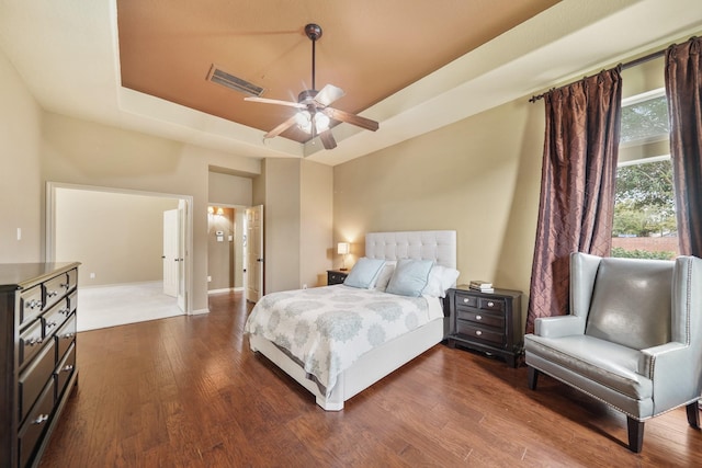 bedroom with ceiling fan, wood-type flooring, and a tray ceiling