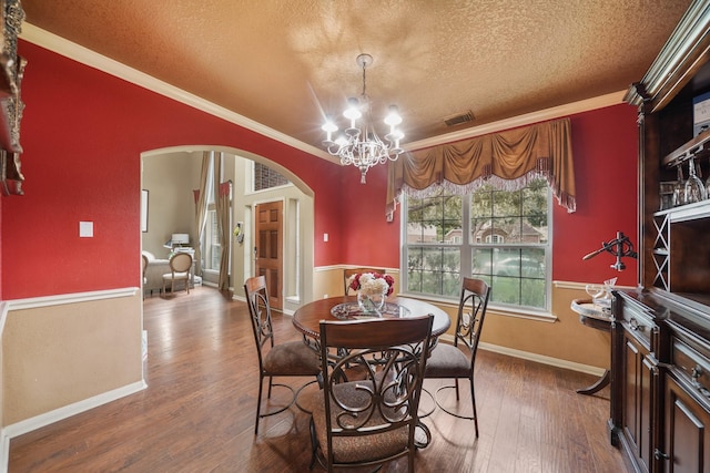 dining room featuring an inviting chandelier, ornamental molding, wood-type flooring, and a textured ceiling