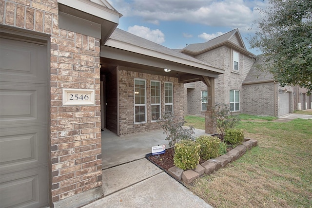 view of exterior entry with a garage and a yard