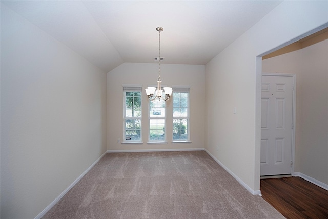 empty room featuring a notable chandelier, vaulted ceiling, and light colored carpet