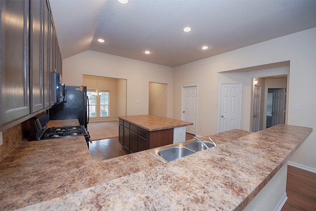 kitchen with vaulted ceiling, sink, dark hardwood / wood-style flooring, stove, and a center island