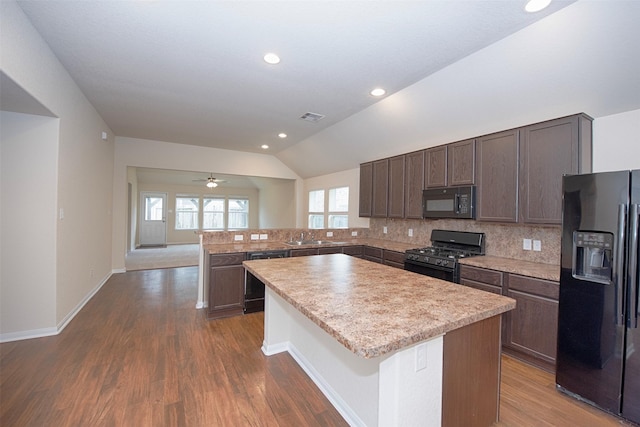 kitchen with vaulted ceiling, sink, decorative backsplash, a center island, and black appliances