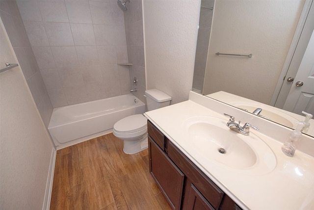 full bathroom featuring vanity, tiled shower / bath combo, wood-type flooring, and toilet