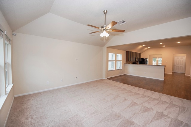 unfurnished living room featuring vaulted ceiling, carpet, and a wealth of natural light