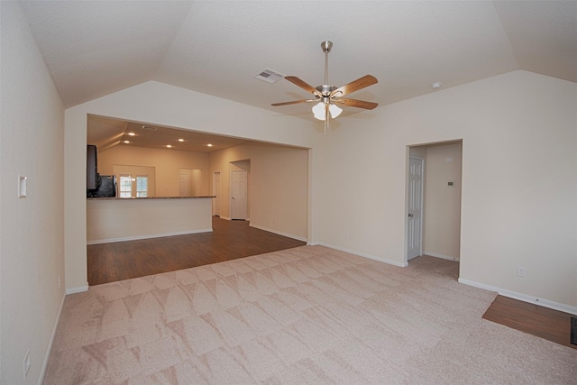 unfurnished living room with vaulted ceiling, carpet floors, and ceiling fan