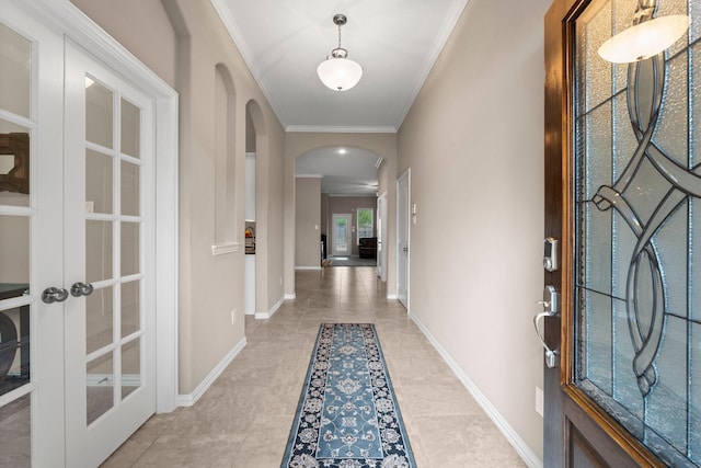 tiled foyer entrance with ornamental molding and french doors