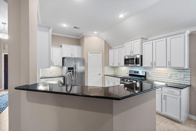 kitchen featuring decorative backsplash, vaulted ceiling, white cabinets, and appliances with stainless steel finishes