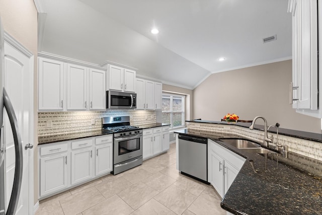 kitchen with vaulted ceiling, appliances with stainless steel finishes, white cabinets, and dark stone counters