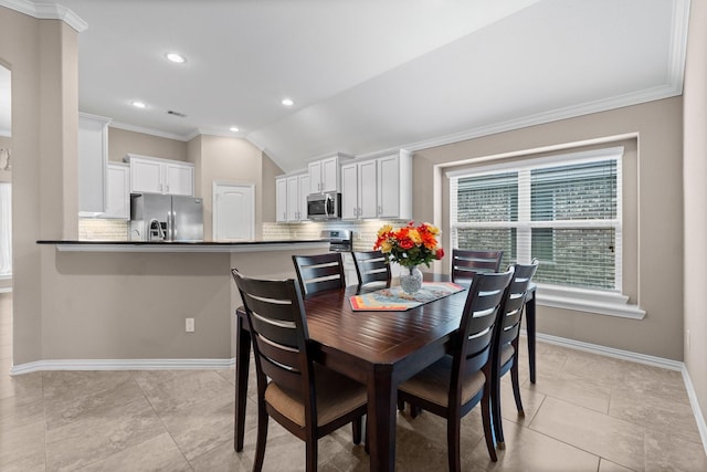 dining area with lofted ceiling, light tile patterned floors, and crown molding