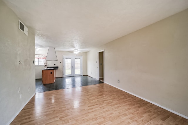 unfurnished living room with hardwood / wood-style floors, a textured ceiling, french doors, and ceiling fan