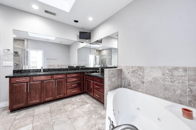 bathroom featuring vanity, separate shower and tub, and a skylight