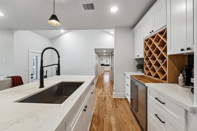 kitchen with light stone countertops, sink, pendant lighting, and white cabinets