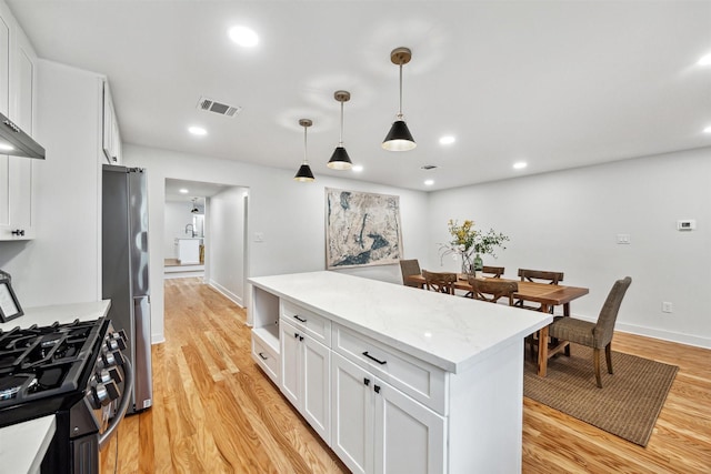 kitchen with white cabinetry, stainless steel appliances, decorative light fixtures, and light hardwood / wood-style floors