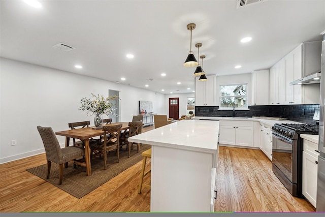 kitchen featuring white cabinetry, sink, hanging light fixtures, a center island, and black gas stove