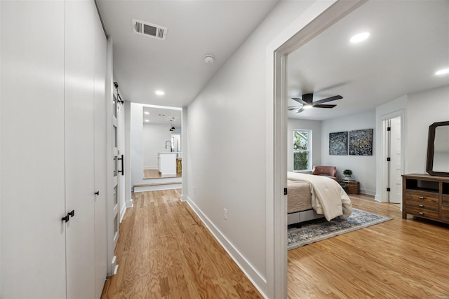 hallway featuring a barn door and light wood-type flooring