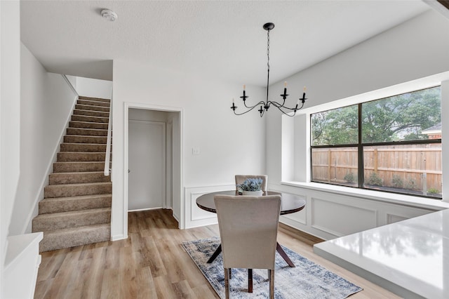 dining space with a textured ceiling, a notable chandelier, and light hardwood / wood-style floors