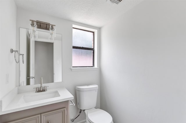 bathroom with vanity, toilet, and a textured ceiling