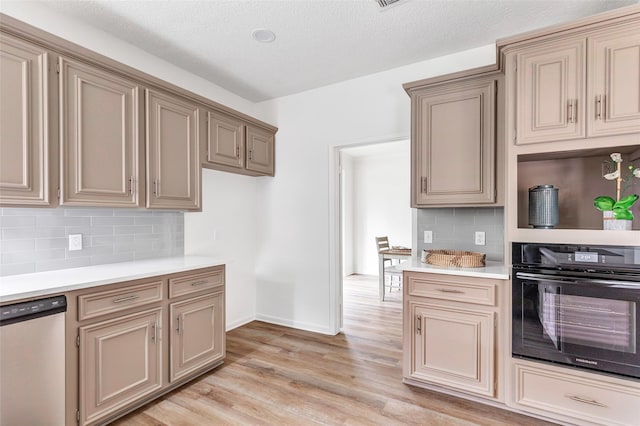 kitchen with light hardwood / wood-style flooring, decorative backsplash, black oven, and dishwasher