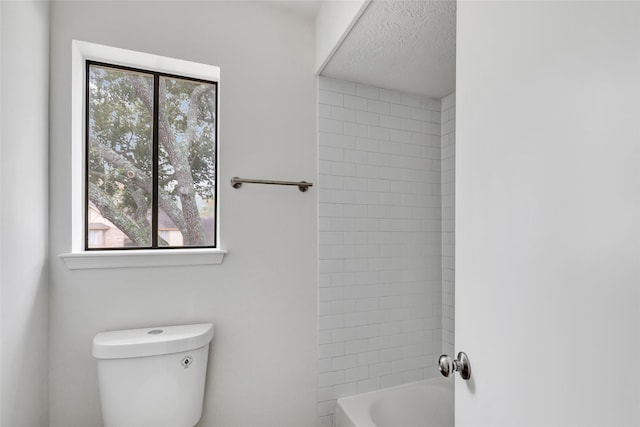 bathroom featuring tiled shower / bath, a healthy amount of sunlight, and toilet