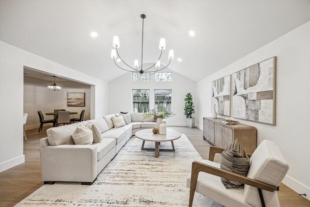 living room with a notable chandelier, hardwood / wood-style flooring, and vaulted ceiling