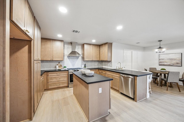 kitchen featuring appliances with stainless steel finishes, a center island, sink, and wall chimney range hood