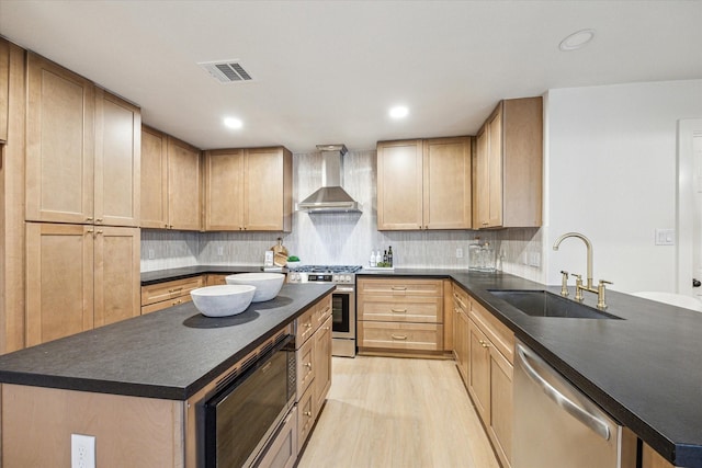 kitchen with a center island, wall chimney range hood, sink, and appliances with stainless steel finishes