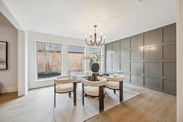 dining space with light wood-type flooring and an inviting chandelier