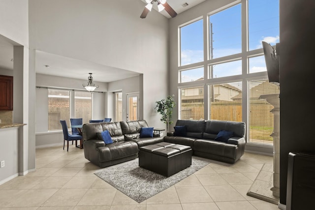 tiled living room with ceiling fan and a high ceiling