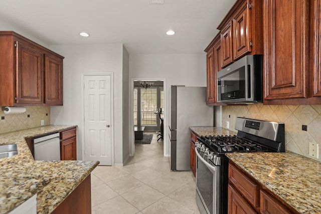 kitchen with light tile patterned flooring, tasteful backsplash, sink, stainless steel appliances, and light stone countertops