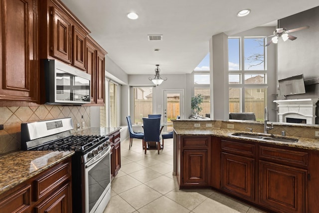 kitchen featuring appliances with stainless steel finishes, decorative light fixtures, sink, decorative backsplash, and light stone countertops