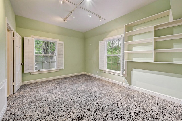 empty room with rail lighting and carpet floors