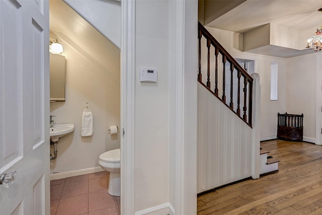 bathroom featuring an inviting chandelier, wood-type flooring, and toilet