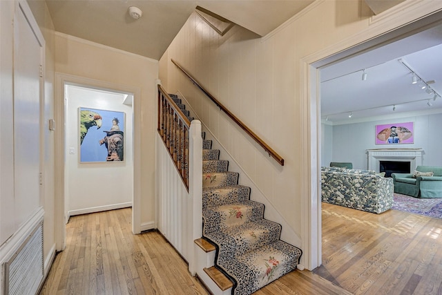 stairs featuring crown molding, track lighting, and hardwood / wood-style floors