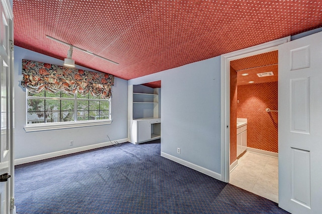 carpeted spare room featuring rail lighting